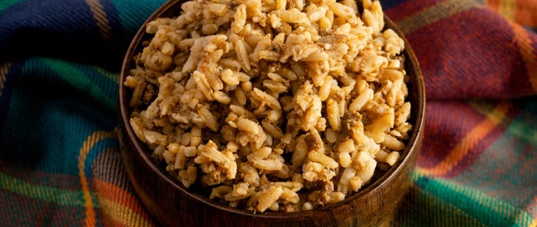 Photo of Cajun Dirty Rice Dressing in a wooden bowl on checkered cloth