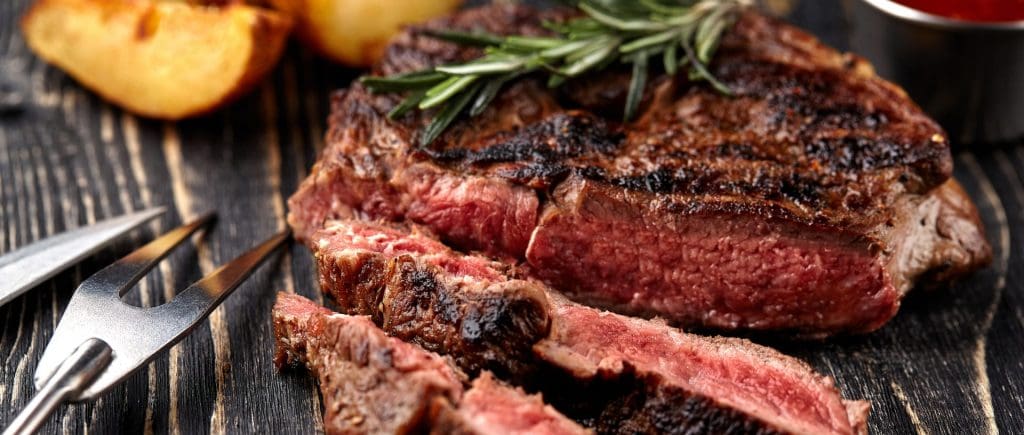 Photo of Cooked Flank Steak Cut and paired with herbs